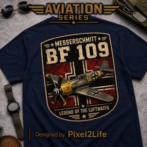 May include: Navy blue t-shirt featuring a vintage graphic of a Messerschmitt BF 109 aircraft. The design includes the text "MESSERSCHMITT BF 109" and "LEGEND OF THE LUFWAFFE" in a distressed style. The shirt is part of the Aviation Series.
