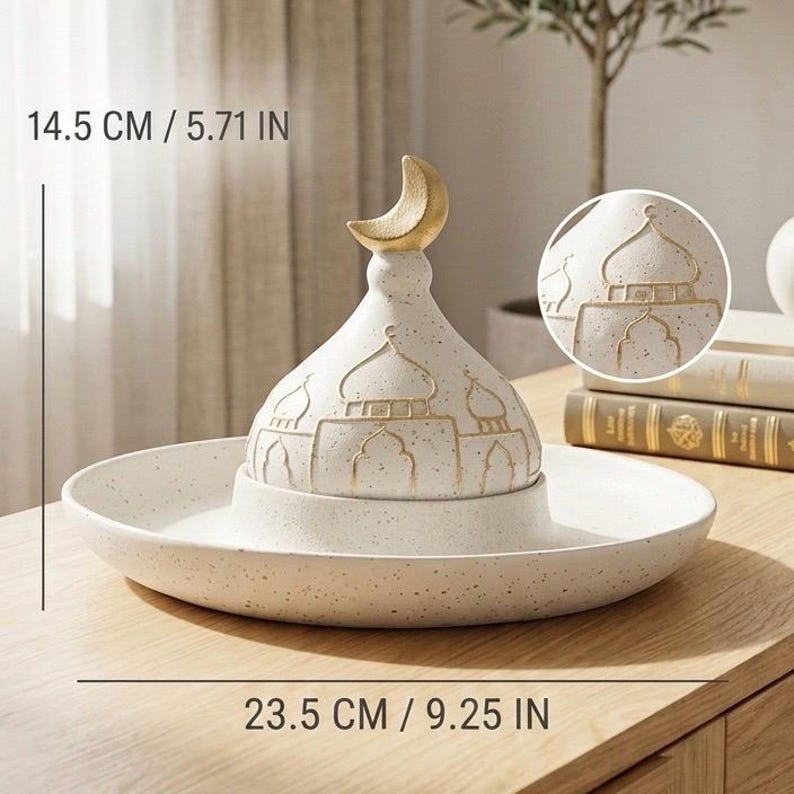 May include: A white ceramic decorative piece with a mosque dome design and a crescent moon finial. The piece is 14.5 cm tall and 23.5 cm wide, with gold accents. The design includes detailed mosque architecture.