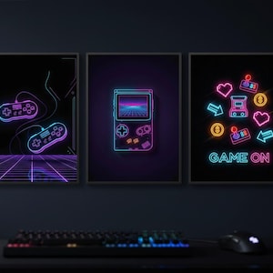 Pode incluir: Três quadros de parede com gráficos de jogos em estilo neon sobre um fundo preto. O quadro da esquerda mostra dois controles, o central exibe um console portátil e o da direita apresenta ícones de arcade com o texto GAME ON em destaque.