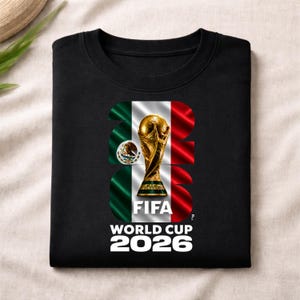 Pu&ograve; includere: Una t-shirt nera con una grande grafica del trofeo della Coppa del Mondo FIFA centrata sulla bandiera messicana. Il design incorpora il numero 2026 con i colori verde, bianco e rosso della bandiera, insieme al testo FIFA WORLD CUP 2026.