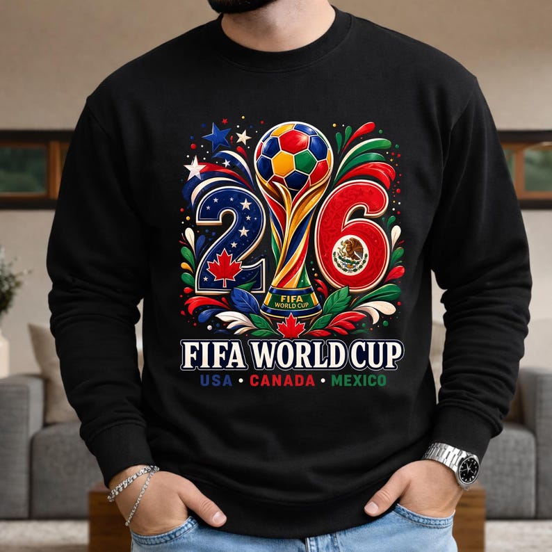 May include: Black sweatshirt featuring a colorful graphic for the 2026 FIFA World Cup. The design includes a trophy, soccer ball, and the numbers 2 and 6. The text "FIFA WORLD CUP" is displayed below, with "USA CANADA MEXICO" underneath.