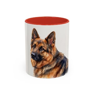 May include: White ceramic mug with a red interior. The mug displays a watercolour illustration of a German Shepherd dog. The dog has brown and black fur and a focused expression.