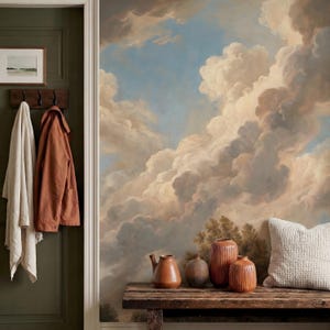 Könnte beinhalten: Ein Raum mit einem Wandbild eines bewölkten Himmels. Eine Holzbank beherbergt Terrakotta-Vasen und ein Kissen. Ein Mantel und ein Handtuch hängen an Haken an einer dunkelgrünen Tür. Ein gerahmtes Landschaftsbild befindet sich über den Haken.