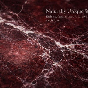 May include: Close-up of a richly textured stone surface. The stone is a deep burgundy colour with white veining throughout. The text "Naturally Unique Stone" and "Each tray features one-of-a-kind veining and texture" is visible.