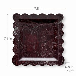 May include: A square serving tray with a scalloped edge. The tray measures 19.8 cm by 19.8 cm and is 2 cm high. It has a dark red marble pattern with white veining. Suitable for serving food or displaying items.