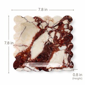 May include: A square marble tray with a wavy edge, measuring 19.8 cm on each side and 2 cm in height. The tray features a cream-colored background with striking red and brown veining throughout.