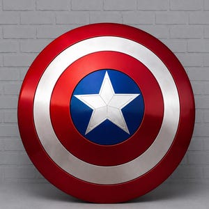 May include: A round shield with a red, white, and blue color scheme. The shield features a red outer ring, a silver middle ring, and a blue center with a white star. The shield is a replica of a superhero's iconic accessory.