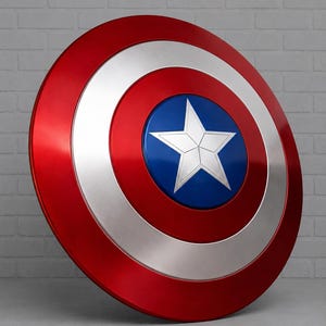 May include: A red, white, and blue shield with a star emblem. The shield has a metallic finish and a circular design. The outer ring is red, followed by a silver ring, a blue center, and a white star.