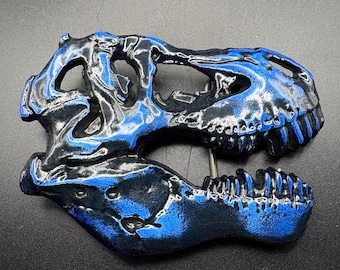 May include: A detailed, close-up view of a dinosaur skull, featuring a striking blend of black and blue hues. The skull's intricate details are highlighted by the contrasting colors, creating a visually appealing and unique decorative piece.