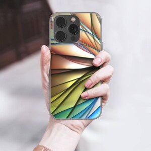 May include: A clear phone case with a colorful abstract design. The design features layered shapes in shades of orange, yellow, green, and blue. The phone case is held in a person's hand.
