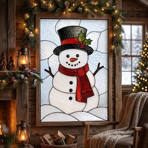 May include: A stained glass window panel featuring a snowman with a black top hat, a red scarf, and an orange carrot nose. The snowman is depicted against a textured white background with black lead lines, framed in wood and hung on a wall.