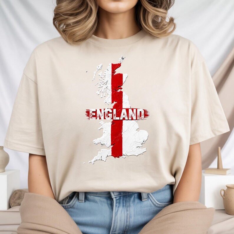 以下が含まれることがあります： イングランドの地図に赤と白の十字が重ねられたベージュのTシャツ。地図には赤で「ENGLAND」の文字がプリントされています。カジュアルなクルーネックのTシャツで、普段使いに適しています。