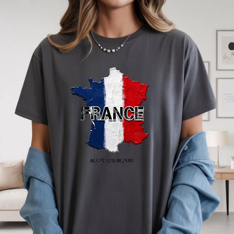 以下が含まれることがあります： フランスの国旗の色（青、白、赤）で描かれたフランスの地図が特徴のダークグレーのTシャツ。「FRANCE」の文字が地図の上にプリントされています。地図の下には「ALLEZ LES BLEUS！」と書かれています。