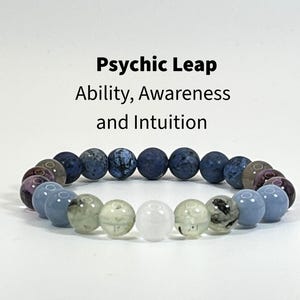 May include: A beaded bracelet featuring a gradient of smooth, round stones in shades of dark blue, light blue, translucent green, and a single clear white bead. The text Psychic Leap Ability, Awareness and Intuition is printed above the bracelet.