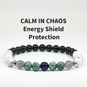 May include: A beaded bracelet featuring a mix of black, white, gray, turquoise, and navy blue stones. The bracelet has the text "CALM IN CHAOS Energy Shield Protection" above it. The beads are strung on an elastic band.