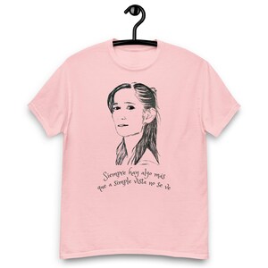 Puede incluir: Camiseta rosa claro con un boceto en blanco y negro de un rostro. El texto "Siempre hay algo más que a simple vista no se ve" está impreso debajo del retrato.