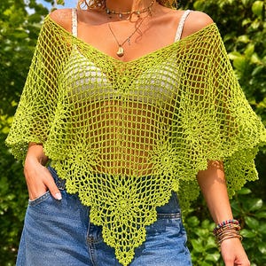 Könnte beinhalten: Ein limettengrünes, offen gewebtes Häkeltop mit V-Ausschnitt und gewelltem Saum. Das Top wird über einem weißen Top getragen und mit einer blauen Jeans kombiniert. Das Häkeldesign weist florale Muster am Saum und an den Ärmeln auf.