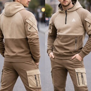 May include: Two-tone brown hooded sweatshirt and matching cargo pants. The sweatshirt has a quarter-zip closure, a small logo on the chest, and multiple pockets. The pants also feature cargo pockets with zippers. The outfit is made of a soft, comfortable material.