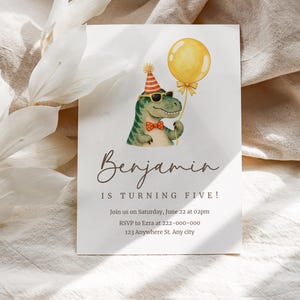 Puede incluir: Una tarjeta de invitación de cumpleaños blanca con un dinosaurio verde que lleva un sombrero de fiesta a rayas rojas y blancas, gafas de sol y una pajarita naranja de lunares, sosteniendo un globo amarillo. El texto dice Benjamin IS TURNING FIVE! Join us on Saturday, June 22 at 02pm RSVP to Ezra at 222-000-000 123 Anywhere St. Any city.