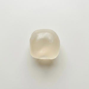 May include: A smooth, off-white, rounded object with a slightly translucent appearance. The object has a soft, organic shape and is set against a plain white background. The lighting creates subtle highlights and shadows.
