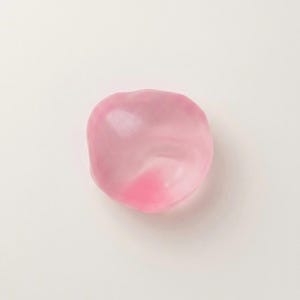 May include: A translucent, pink, rounded object with a darker pink area. The object is smooth and appears to be made of a gel-like material. The background is plain white.