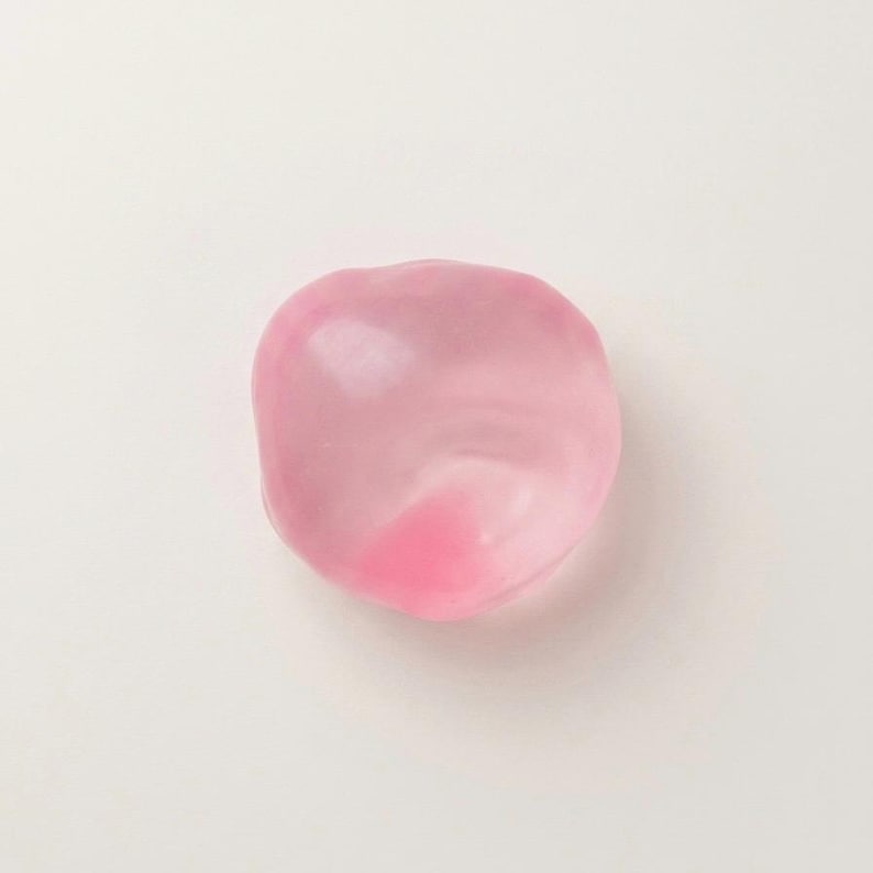 May include: A translucent, pink, rounded object with a darker pink area. The object is smooth and appears to be made of a gel-like material. The background is plain white.