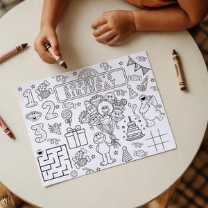 Puede incluir: Una página para colorear en blanco y negro con personajes de Barrio Sésamo, el texto "SOPHIA'S BIRTHDAY", números e ilustraciones de fiesta. Hay crayones sobre la mesa, listos para colorear.