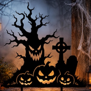 May include: A black metal silhouette yard decoration featuring a gnarled tree with a jagged face, three carved pumpkins with glowing eyes and mouths, and a Celtic cross tombstone, all arranged on a flat base for outdoor display.
