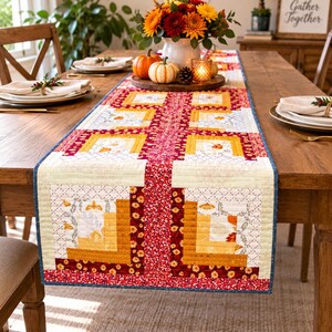 Puede incluir: Un camino de mesa acolchado rectangular con un diseño de patchwork en colores otoñales que incluyen rojo intenso, amarillo dorado y crema. La tela presenta patrones florales y de hojas con una franja vertical central de pequeñas flores rojas.