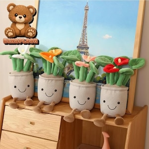 May include: Four plush calla lily plants with smiling faces in beige pots. Each plant has green leaves and a different colored flower: white, orange, pink, and red. The background features a painting of the Eiffel Tower.