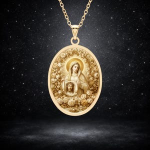 Op de afbeelding: Een goudkleurige ovale hanger aan een ketting met een gegraveerde afbeelding van een vrouw die een doek met een gezicht erop vasthoudt, omringd door een gedetailleerde bloemenrand. De hanger hangt aan een bijpassende goudkleurige metalen ketting.