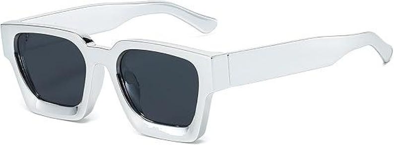 Puede incluir: Gafas de sol plateadas con lentes oscuras. Las gafas tienen forma rectangular con una montura gruesa y patillas rectas. Las lentes son de color gris oscuro y la montura tiene un acabado met&aacute;lico brillante. Las gafas est&aacute;n dise&ntilde;adas para la protecci&oacute;n ocular.