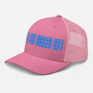 May include: A pink trucker hat with a curved brim and mesh back. The front of the hat features the blue text "FUN BEACH GUY" stacked vertically. The hat has a snapback closure.
