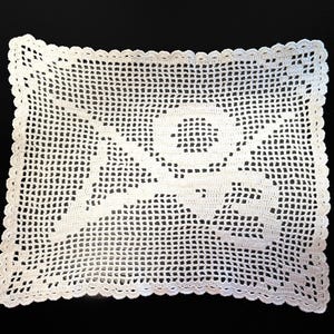 May include: A rectangular, off-white crocheted doily with a floral design in the center. The edges are scalloped, and the open weave pattern is visible throughout. The doily is likely handmade and suitable for home decor.