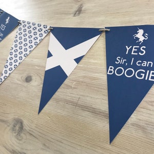 May include: A blue and white bunting with a Scottish flag design and a flag that says "YES Sir, I can BOOGIE" with a unicorn illustration.