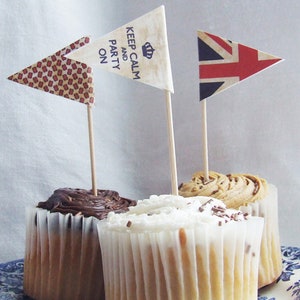Könnte beinhalten: Drei Cupcakes mit verschiedenen Frostings und Toppings. Die Cupcakes sind mit kleinen Flaggen verziert. Eine Flagge sagt "Keep Calm and Party On", eine andere ist eine Union Jack Flagge und die dritte ist eine gemusterte Flagge.