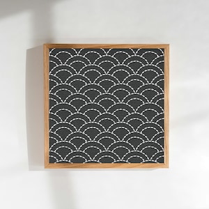 May include: Square framed artwork featuring a repeating pattern of white stitched arcs on a dark gray background. The artwork is encased in a natural wood frame, creating a minimalist and modern aesthetic. The design is reminiscent of traditional Japanese motifs.