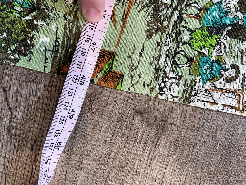 K&ouml;nnte beinhalten: Ein rosa Ma&szlig;band mit wei&szlig;en Markierungen liegt auf einer Holzoberfl&auml;che. Das Band misst 120 bis 128 cm.