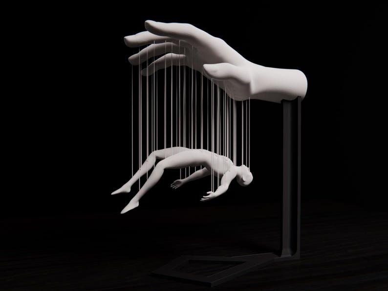 May include: A white sculpture of a hand holding a human figure suspended by strings. The hand and figure are set against a black background, creating a dramatic contrast. The artwork evokes themes of control and manipulation.
