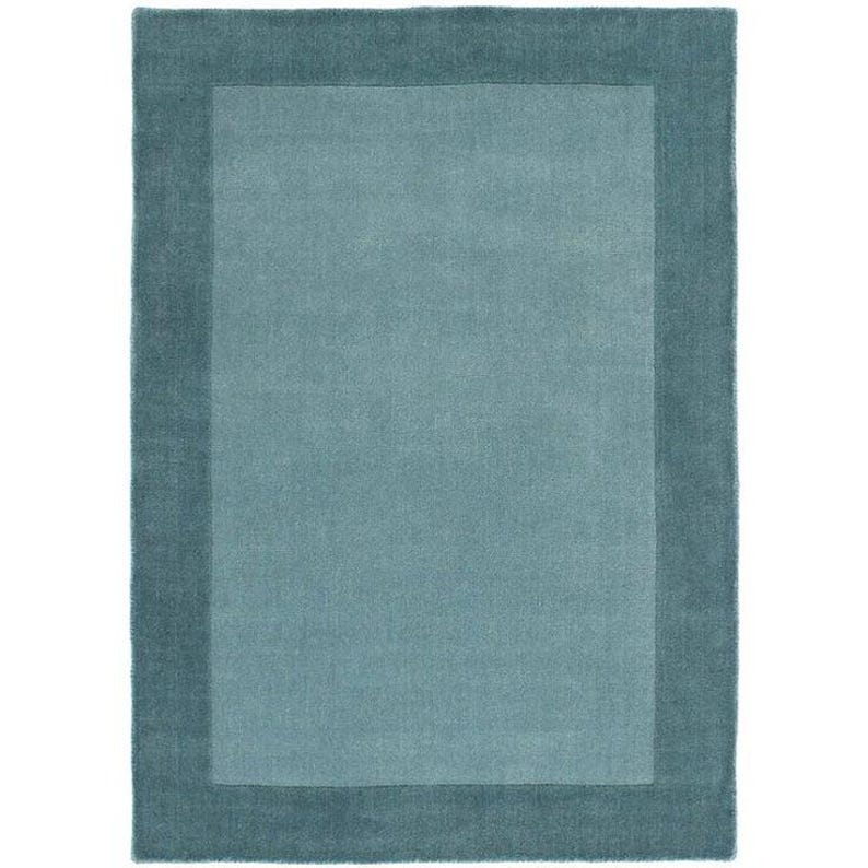 Puede incluir: Una alfombra rectangular con un centro azul verdoso y un borde azul verdoso m&aacute;s oscuro. La alfombra tiene un dise&ntilde;o simple y moderno, adecuado para varios estilos de interior. La textura parece suave y acogedora.