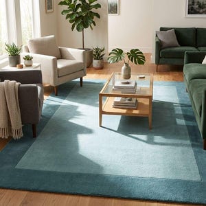 Puede incluir: Una alfombra rectangular en un sal&oacute;n, con un dise&ntilde;o azul de dos tonos. El centro es azul claro, enmarcado por un borde azul oscuro. La habitaci&oacute;n incluye muebles y plantas en macetas.