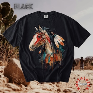 Könnte beinhalten: Schwarzes T-Shirt mit einer Aquarellillustration eines indianischen Pferdes. Das Pferd hat ein weißes Gesicht mit roten Markierungen, verziert mit Federn und Schmuck. Das Wort "BLACK" ist oben aufgedruckt.