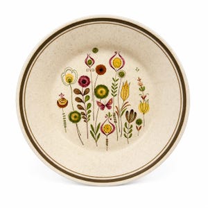 Op de afbeelding: Een rond keramieken bord met een gespikkelde crèmekleurige basis en een donkerbruine rand. Het midden is voorzien van een kleurrijke illustratie van diverse gestileerde bloemen, stengels en bladeren in tinten geel, rood, groen en bruin, met een kleine vlinder.