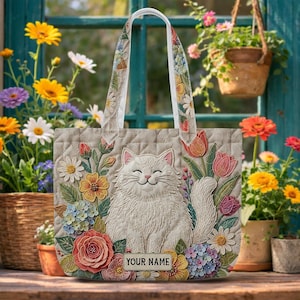 May include: A white ceramic mug with a black handle and the text "But First, Coffee" in a bold, black font. The mug is set against a blurred background, suggesting a cozy setting. The mug appears to be approximately 4 inches tall.