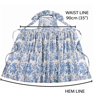 May include: A blue and white apron with a toile pattern. The apron has a waist line of 35 inches and a hem line of 78 inches. The apron has ties at the waist and neck. The apron is made of a lightweight fabric.