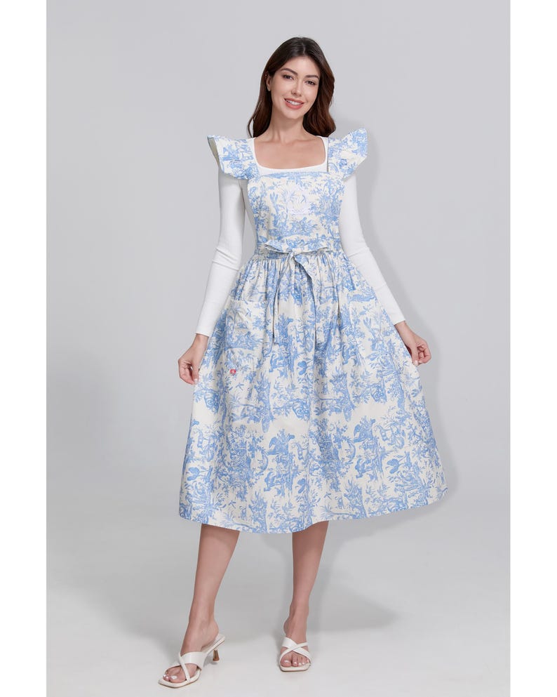 May include: A light blue and white patterned dress with a square neckline and a matching belt. The dress features a floral design and is paired with a white long-sleeved top. The dress is knee-length.