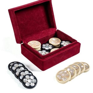 May include: A red velvet box with a set of game pieces. The game pieces are round, with a black or cream-colored base and inlaid mother-of-pearl. The box is open, revealing the game pieces inside.