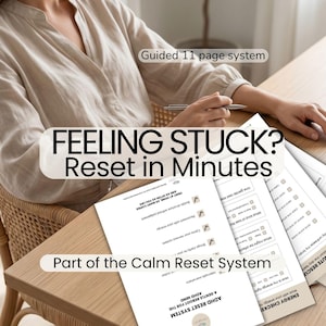 May include: A person sits at a wooden table with several printed pages. The text on the pages reads "Feeling Stuck? Reset in Minutes" and "Part of the Calm Reset System". The image suggests a system for mental well-being.