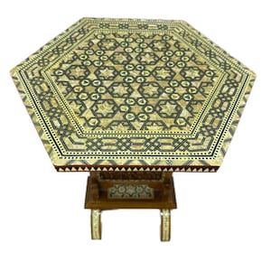 May include: A hexagonal side table featuring intricate geometric marquetry inlay across the top surface. The design incorporates light-coloured wood and mother-of-pearl accents in a star pattern, with a dark wood base and matching inlay on the legs.