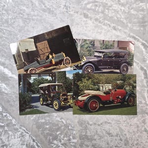 Könnte beinhalten: Vier Oldtimer-Postkarten. Die Postkarten zeigen klassische Autos in verschiedenen Farben, darunter Rot, Schwarz und Grün. Die Autos sind vor Hintergründen im Freien platziert und zeigen ihr historisches Design und ihren Stil.